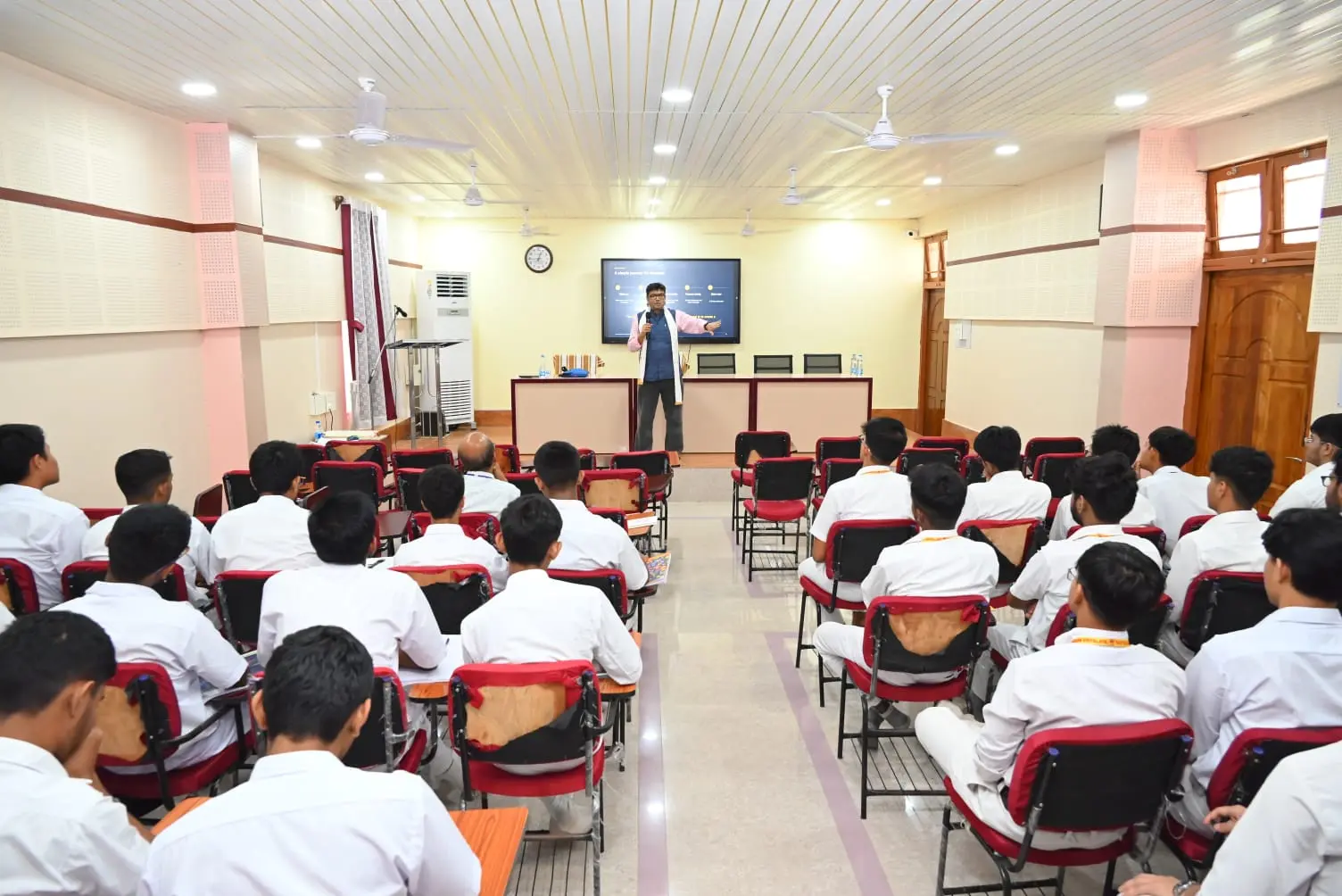Dr. Jayanta Ghosh addressing students in a bright auditorium about choosing problems worth solving instead of jobs